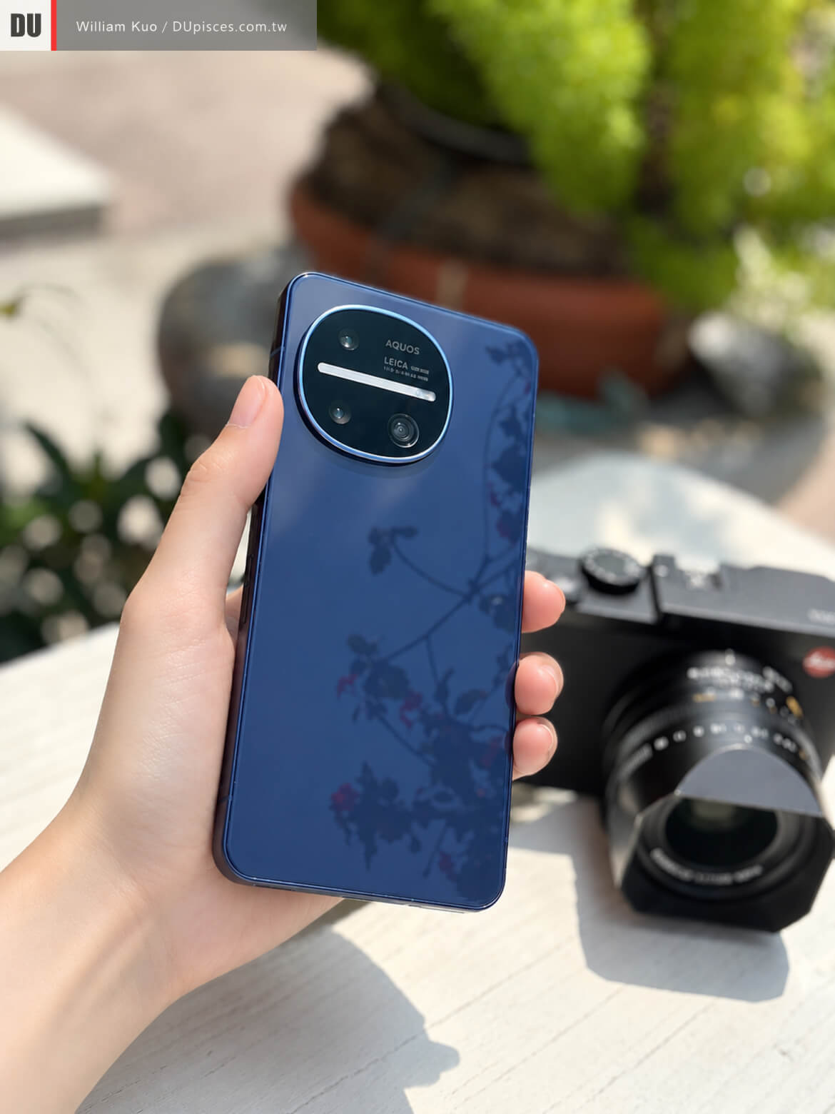攝影師手持 SHARP AQUOS R11 鋼曜藍，鏡面玻璃背蓋與徠卡三鏡頭模組外觀